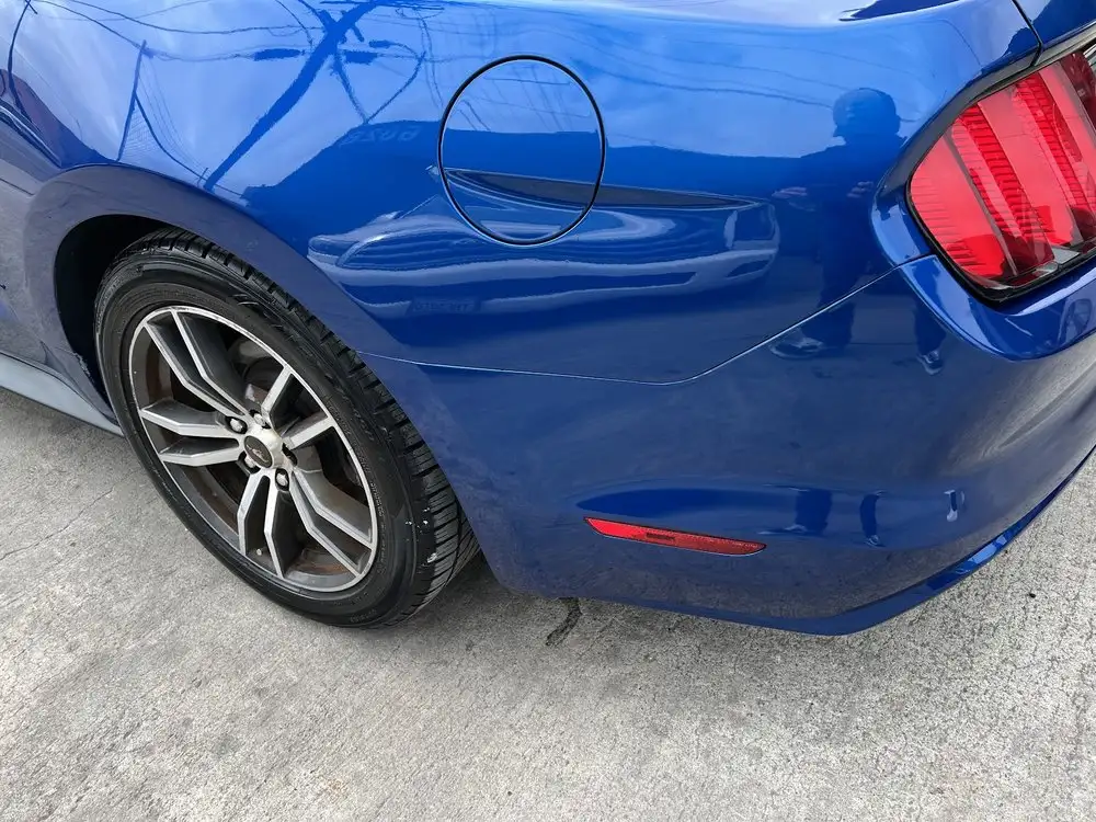 Blue Ford Mustang with a dented rear quarter panel near the fuel door