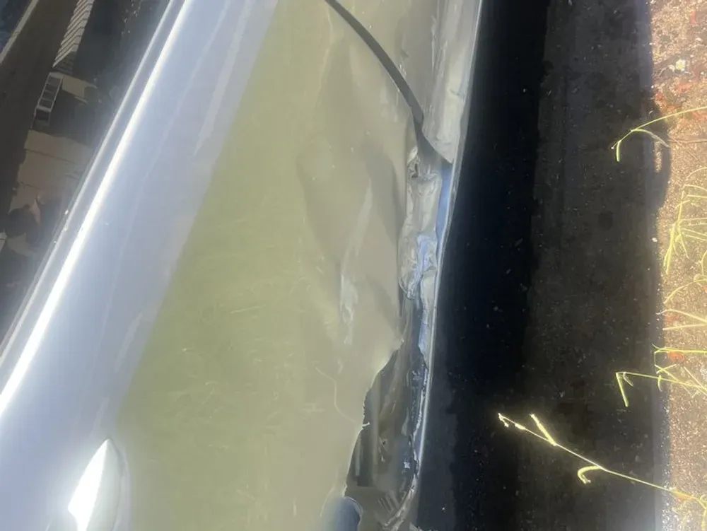 Close-up of a deep scrape and crease along a silver car's lower door